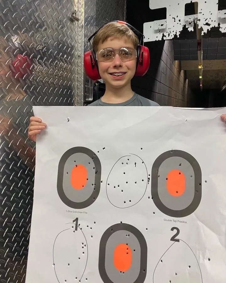 Female student holding target at gun range