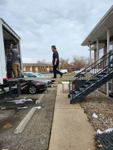 Professional apartment movers in Fort Collins carrying furniture into a second-floor apartment near Colorado State University