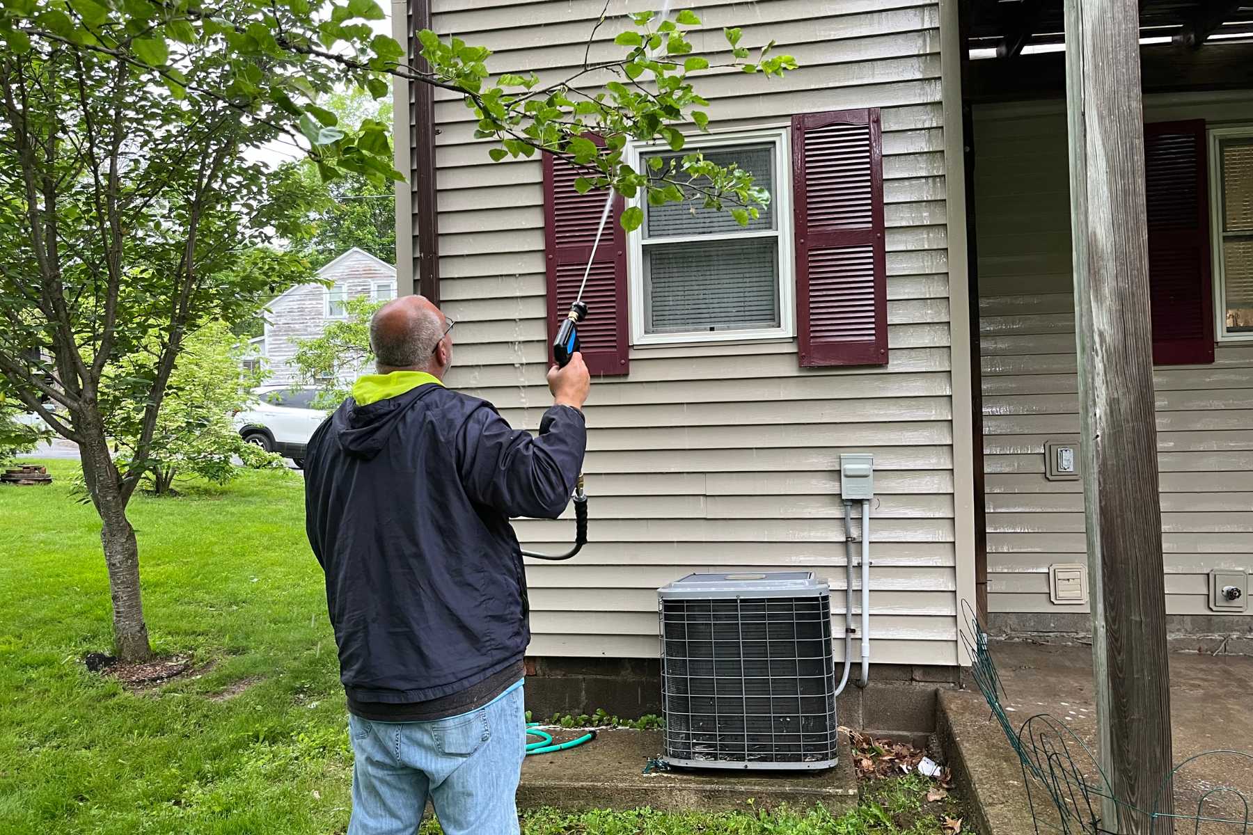 Professional vinyl siding soft washing in Catskill, NY with the Freedom Powerwash owner treating and rinsing algae buildup around windows, shutters, and exterior trim.