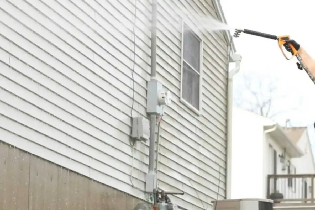 Professional vinyl siding cleaning in Poughkeepsie, NY with the Freedom Powerwash owner using a soft-wash wand to remove algae, grime, and buildup from residential siding.