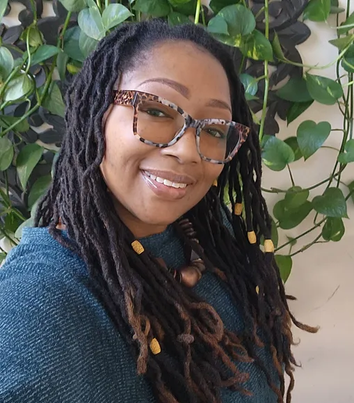 Mellanie Grier outdoors in a natural woodland setting, wearing quiet earth tones