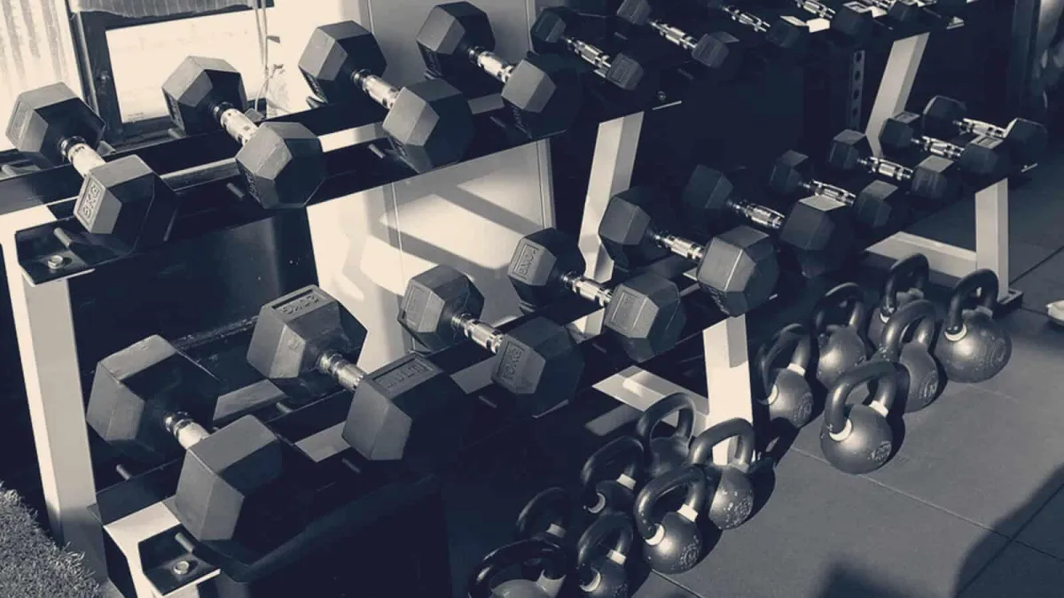 a shirtless man in a gym holding a barbell