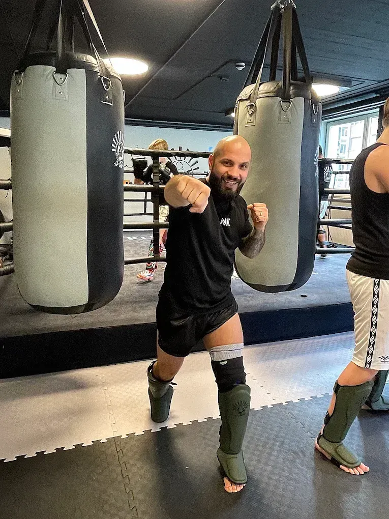 a shirtless man in a gym holding a barbell