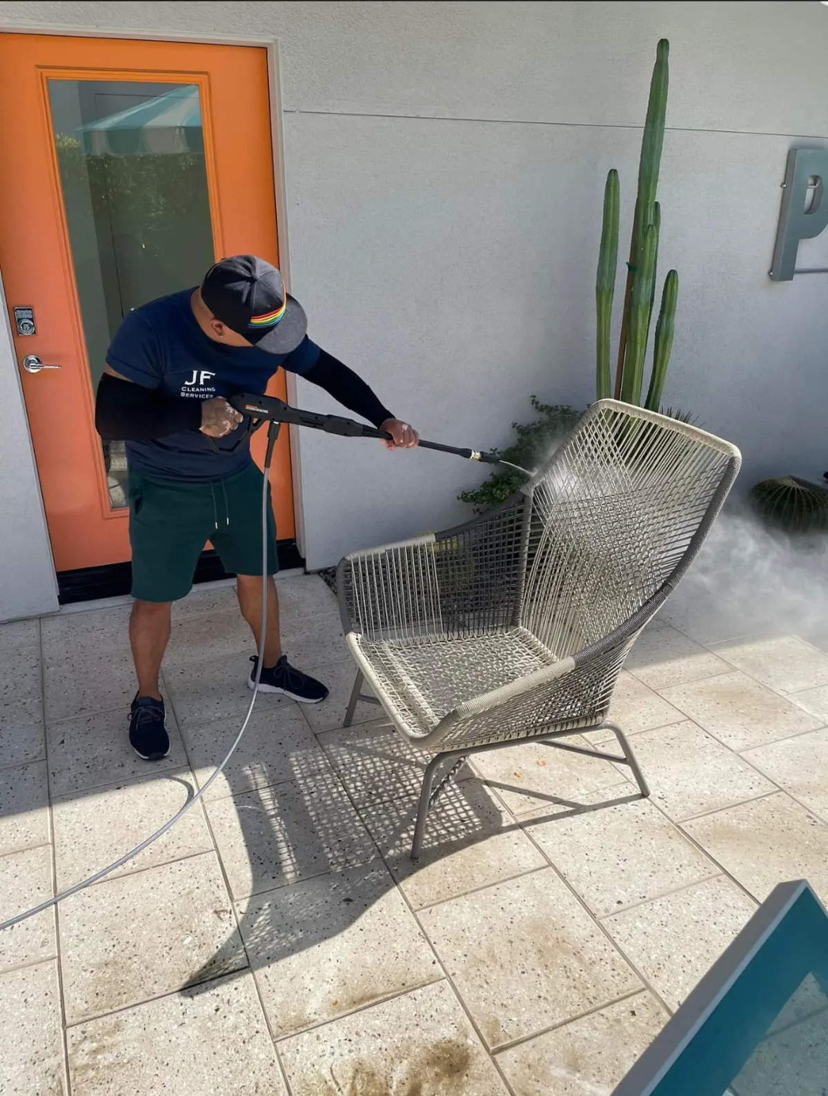 Technician cleaning solar panels on a rooftop with brush and water flow