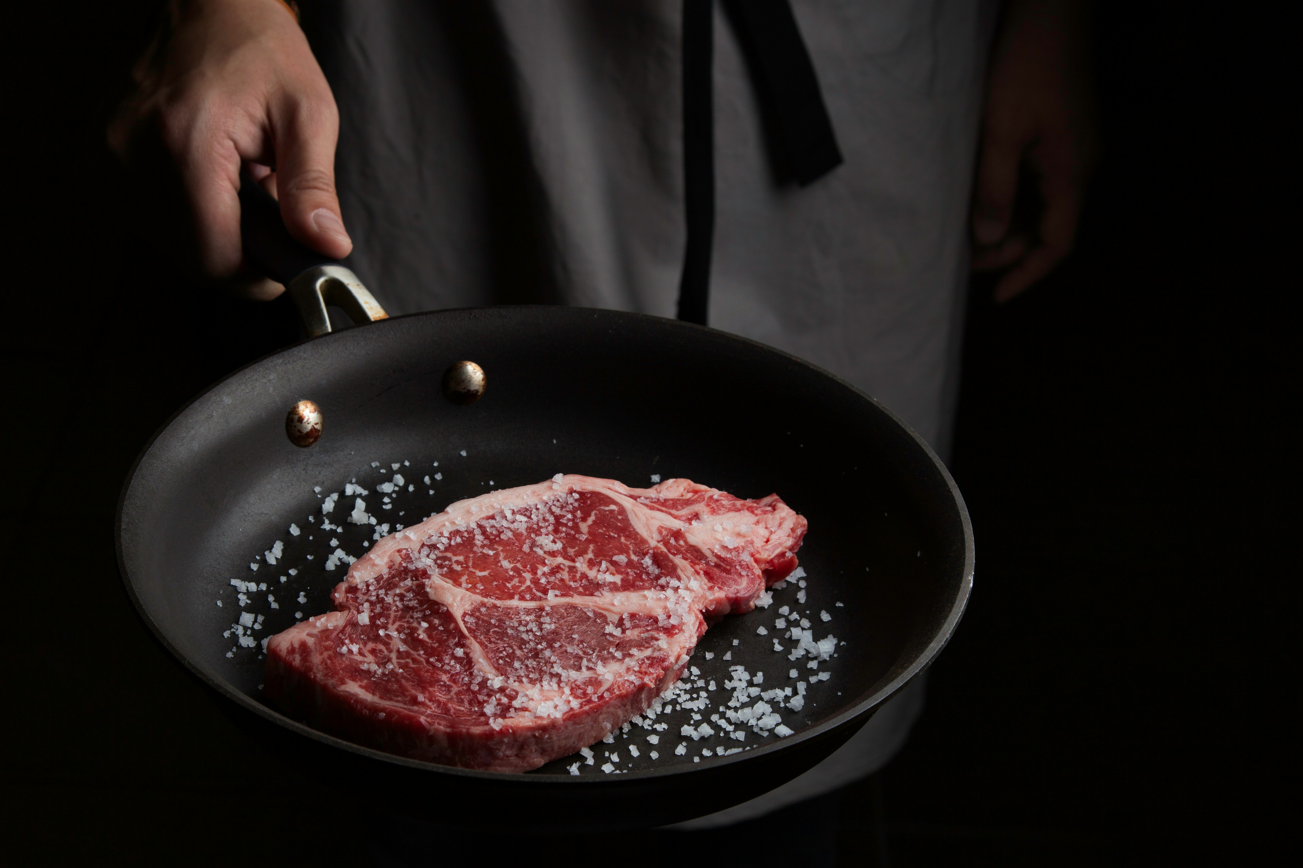 Raw steak with sea salt in a cast iron skillet
