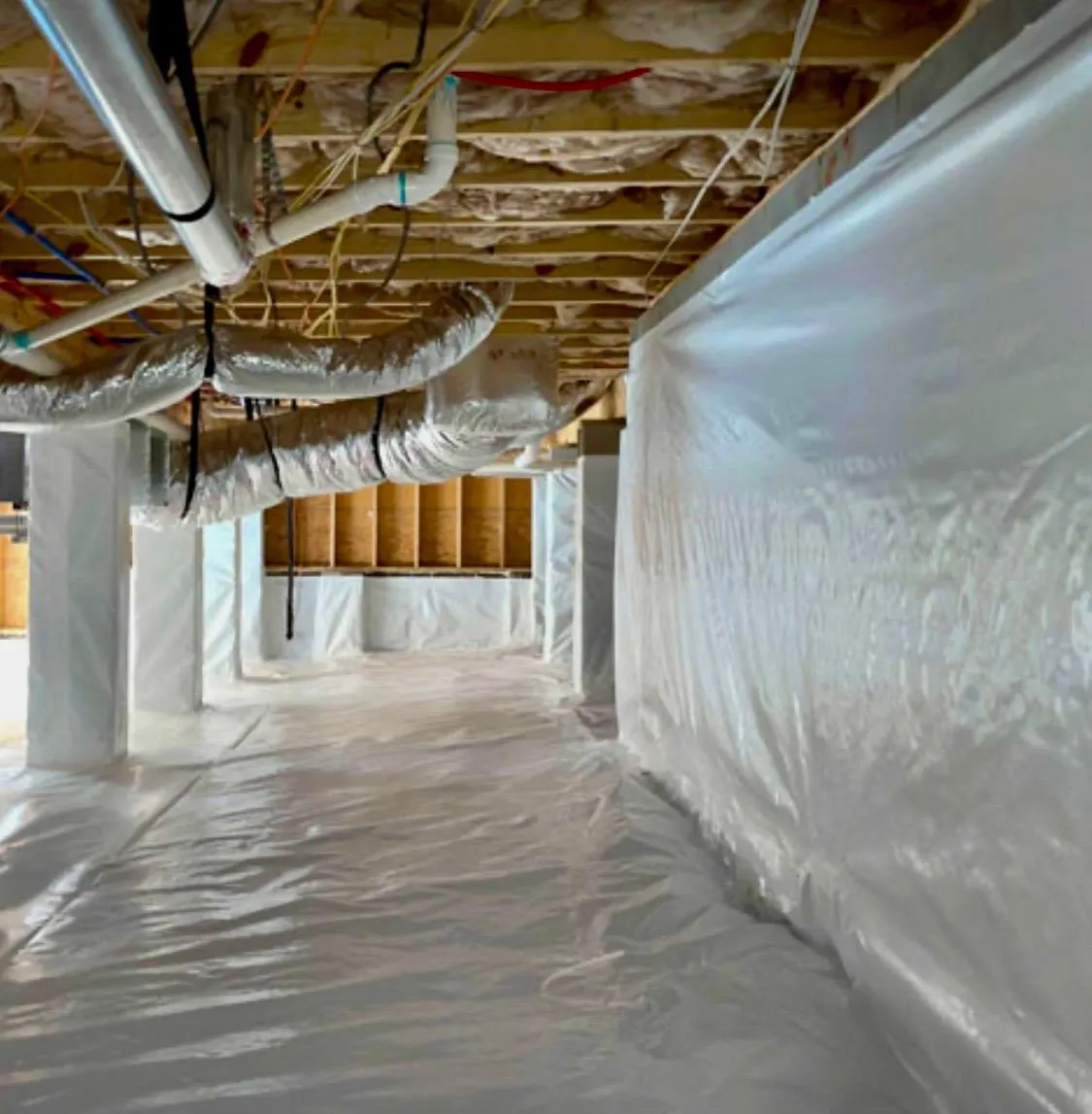 Crawlspace / lower level encapsulation with clean moisture-barrier wall wrap and flooring.