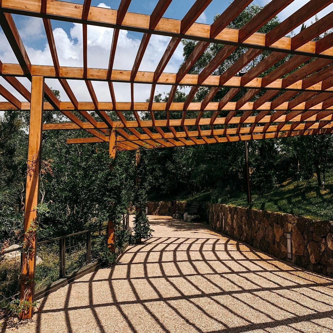 Wooden pergola over curved stone patio with landscaped views.
