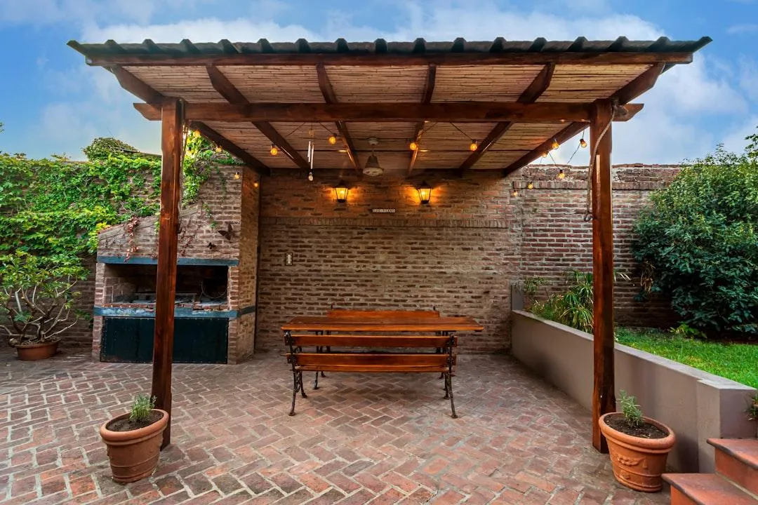 Covered patio with stone flooring and wooden beams overlooking outdoor seating.
