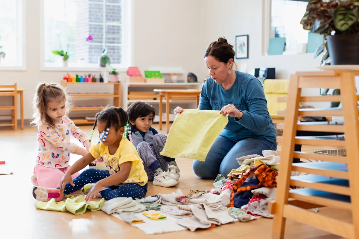 Montessori guide and children folding placemats.