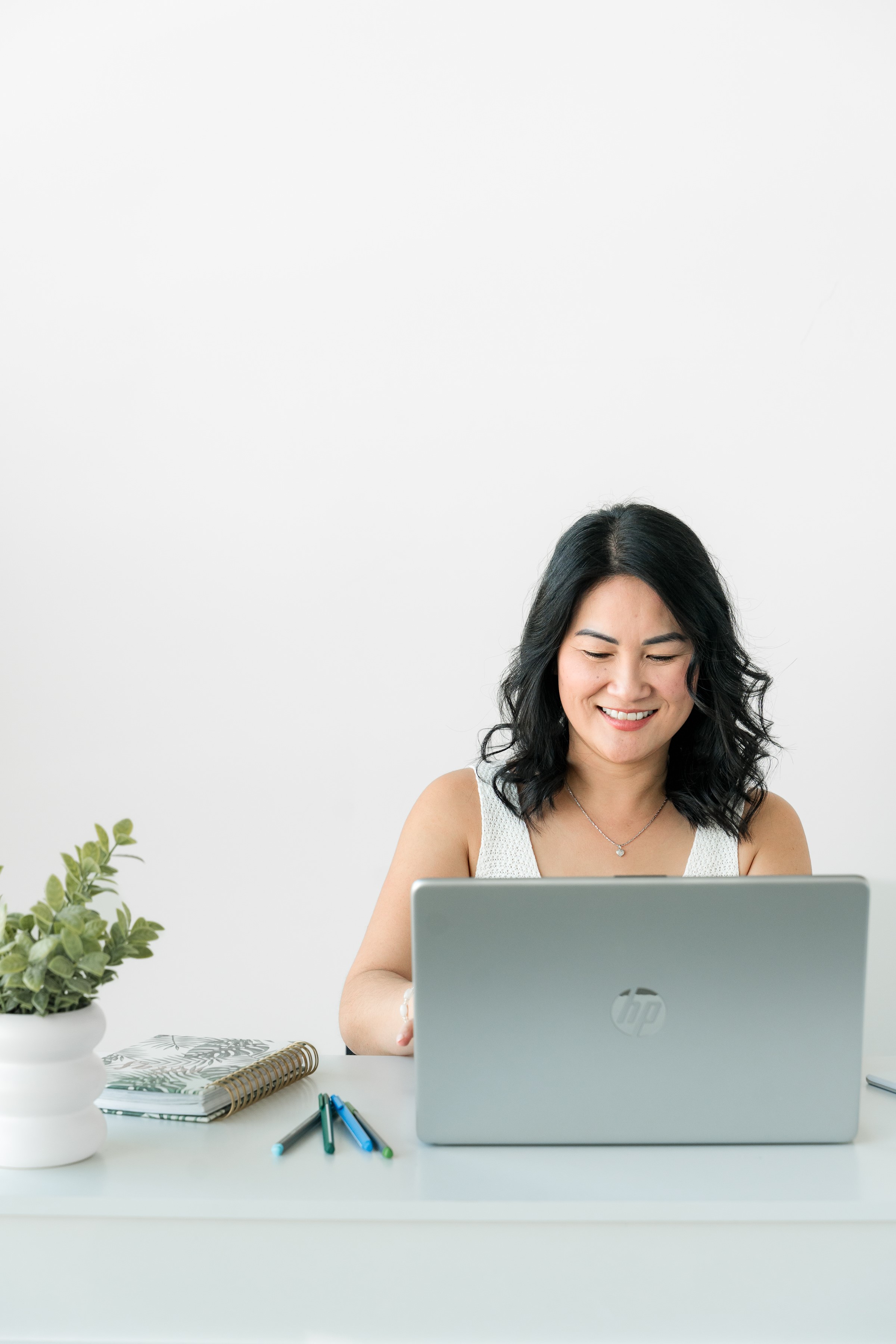 A calm, relieved bookkeeper working in a bright airy space with plants