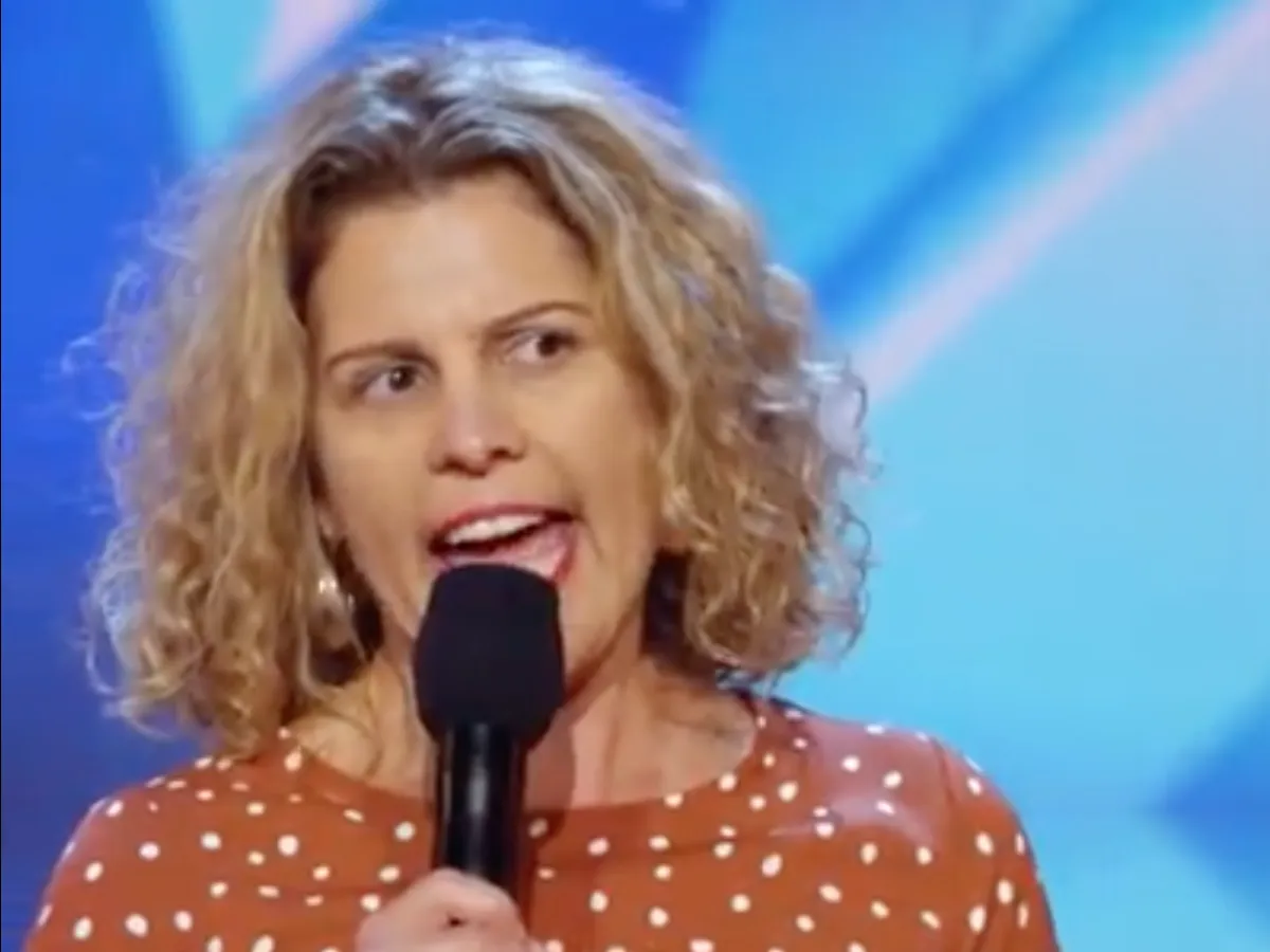 Emma on stage performing stand-up comedy under warm lights