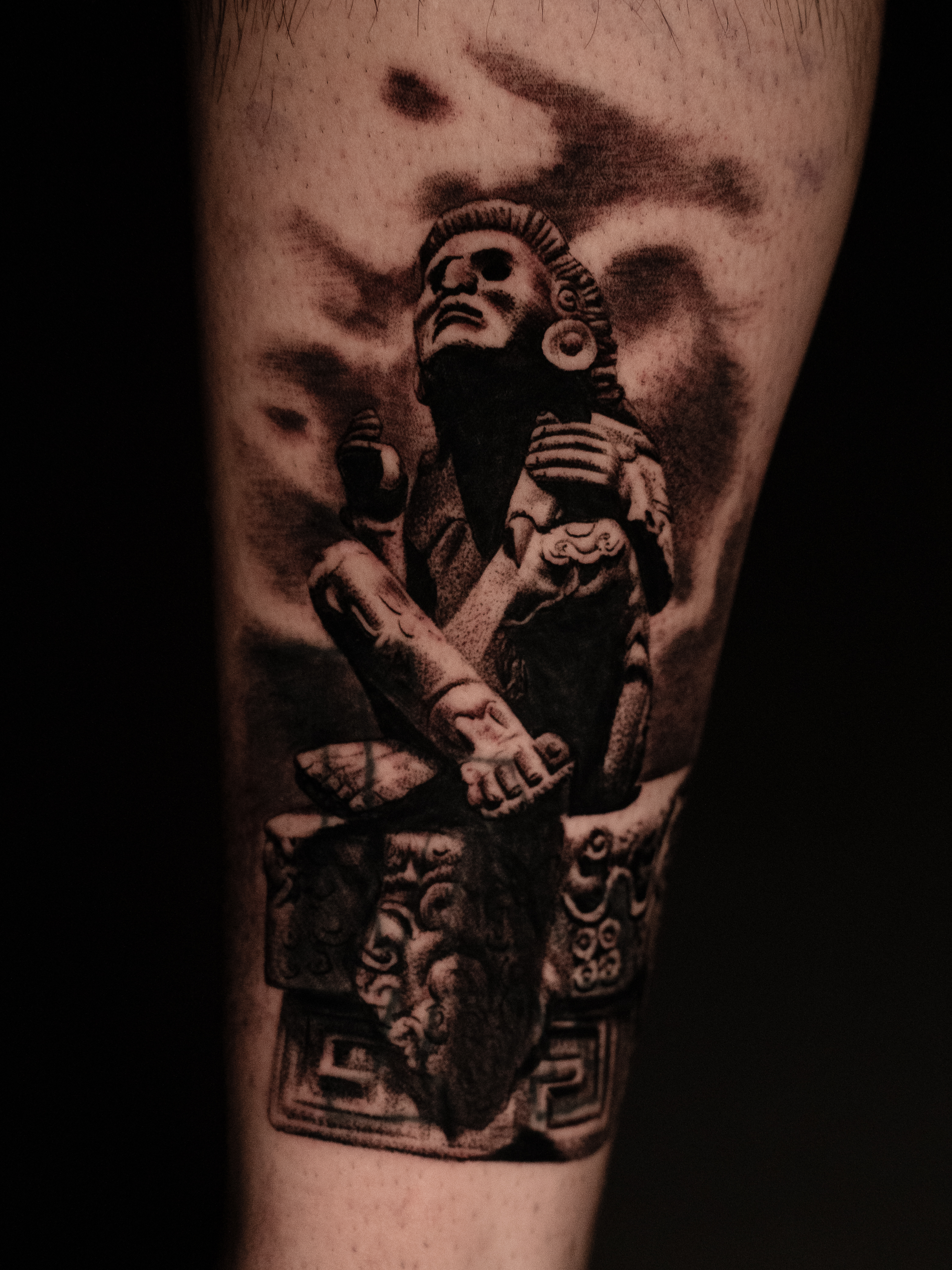 A geometric wolf tattoo in blackwork style, placed on a man’s upper arm. The design features sharp lines, dotwork shading, and abstract shapes forming the wolf’s face. The image is shot in a modern studio with a dark background, highlighting the bold contrast.