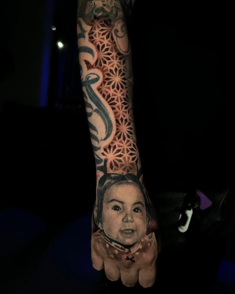 A vibrant, full-back tattoo of a phoenix in flight, with fiery red, orange, and gold feathers. The tattoo is shown on a young man’s back, photographed in a dramatic studio light that highlights the intricate color blending and dynamic movement of the design.