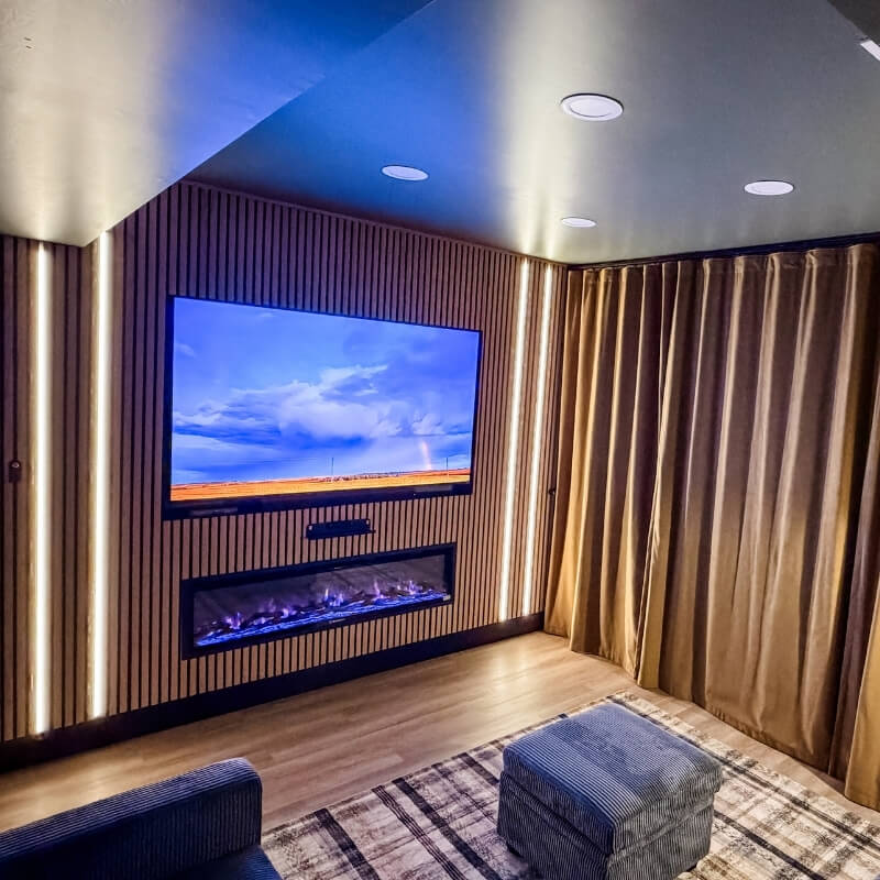 Basement movie room with ambient lighting, fireplace, and large screen TV for cozy movie nights