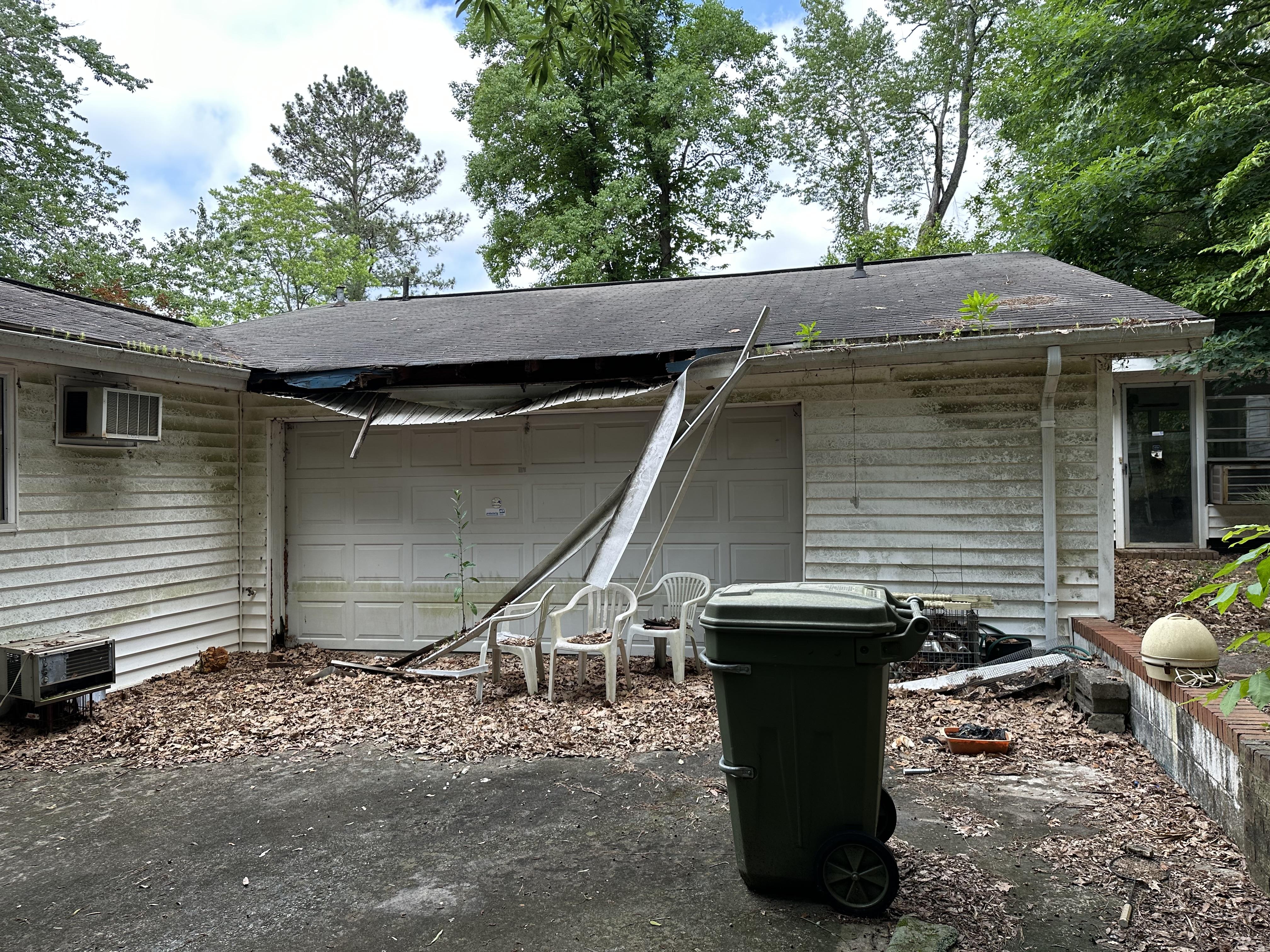 We buy houses as is in Perry GA. Garage area of house with tree damage and missing siding.
