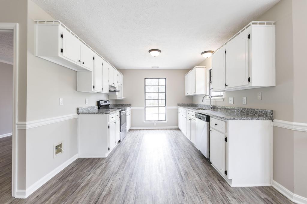 We buy houses in Lilburn Georgia. Remodeled white kitchen with granite countertops.
