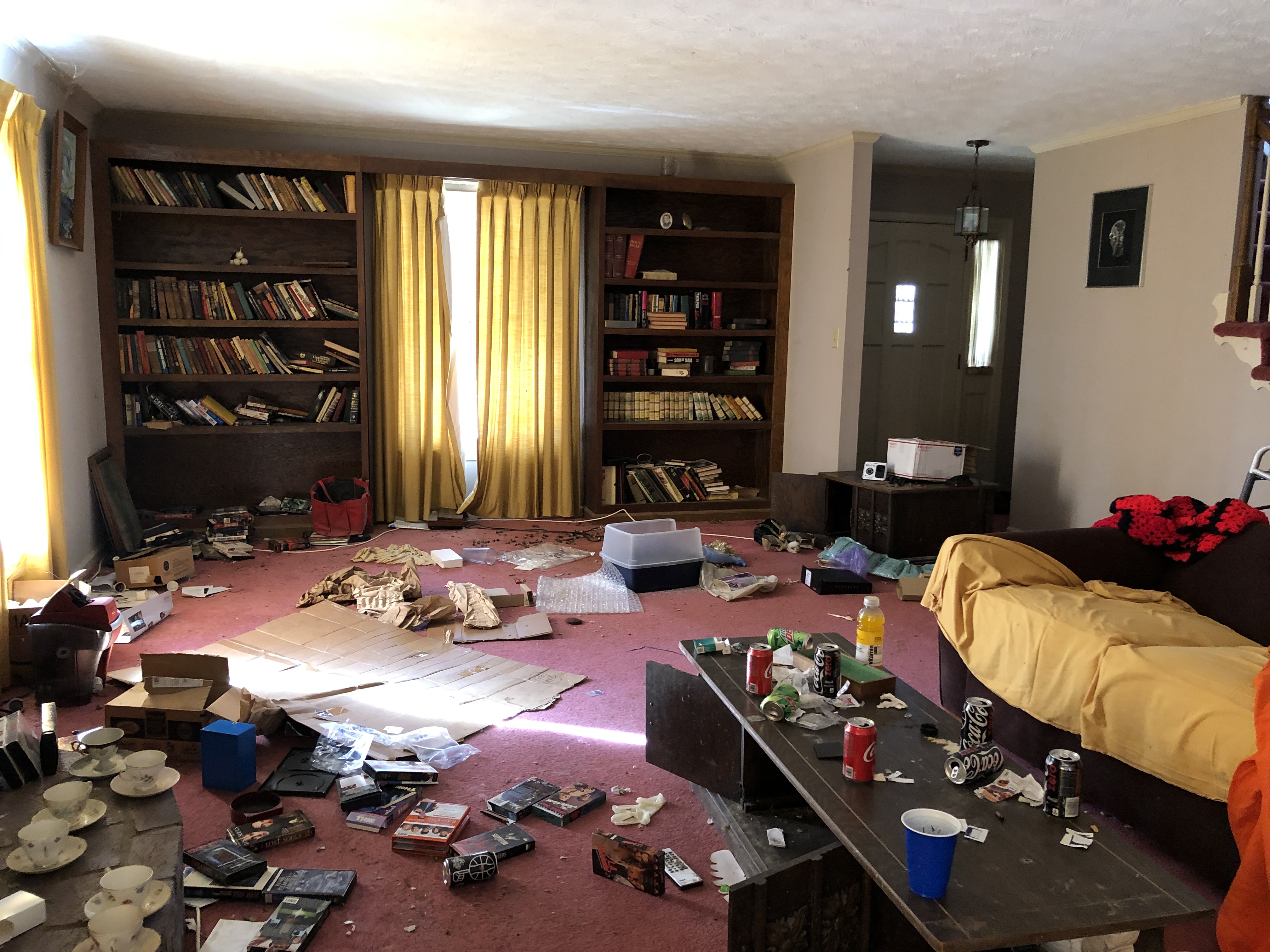 Sell my house as is in Lilburn GA. Living room of abandoned house with old carpet, furniture and trash.