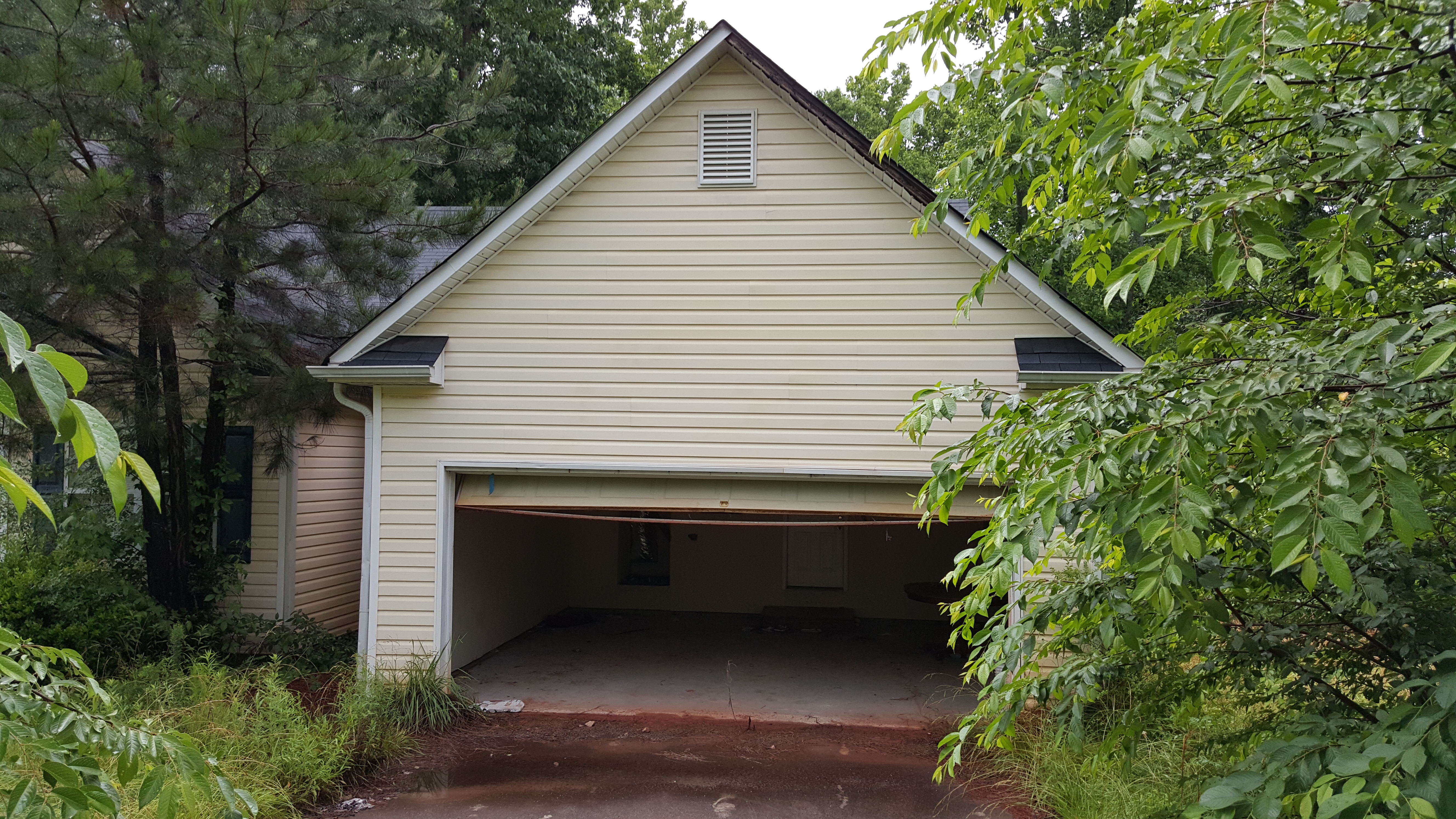 Sell my vacant house. Abandoned house with open garage door.