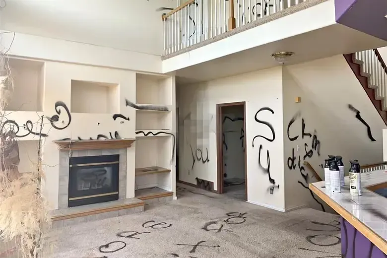Vandalized house with spray paint on walls and carpet.