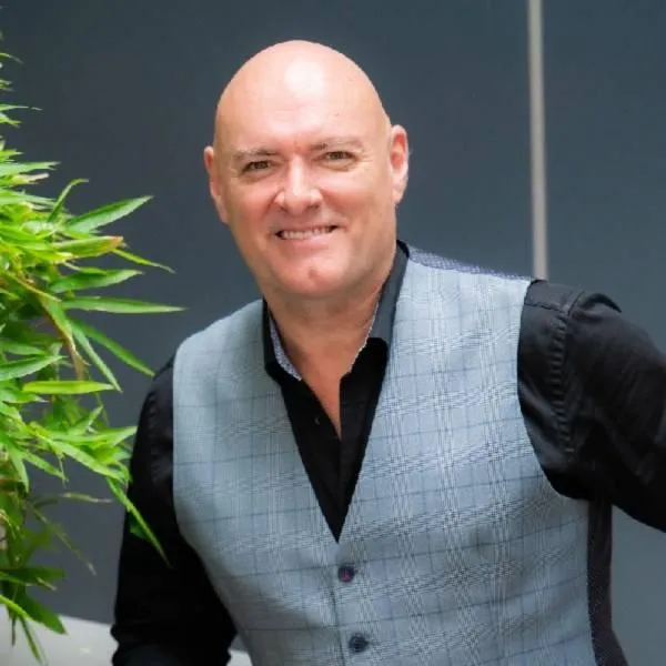 man in blue denim top standing under tree leaf