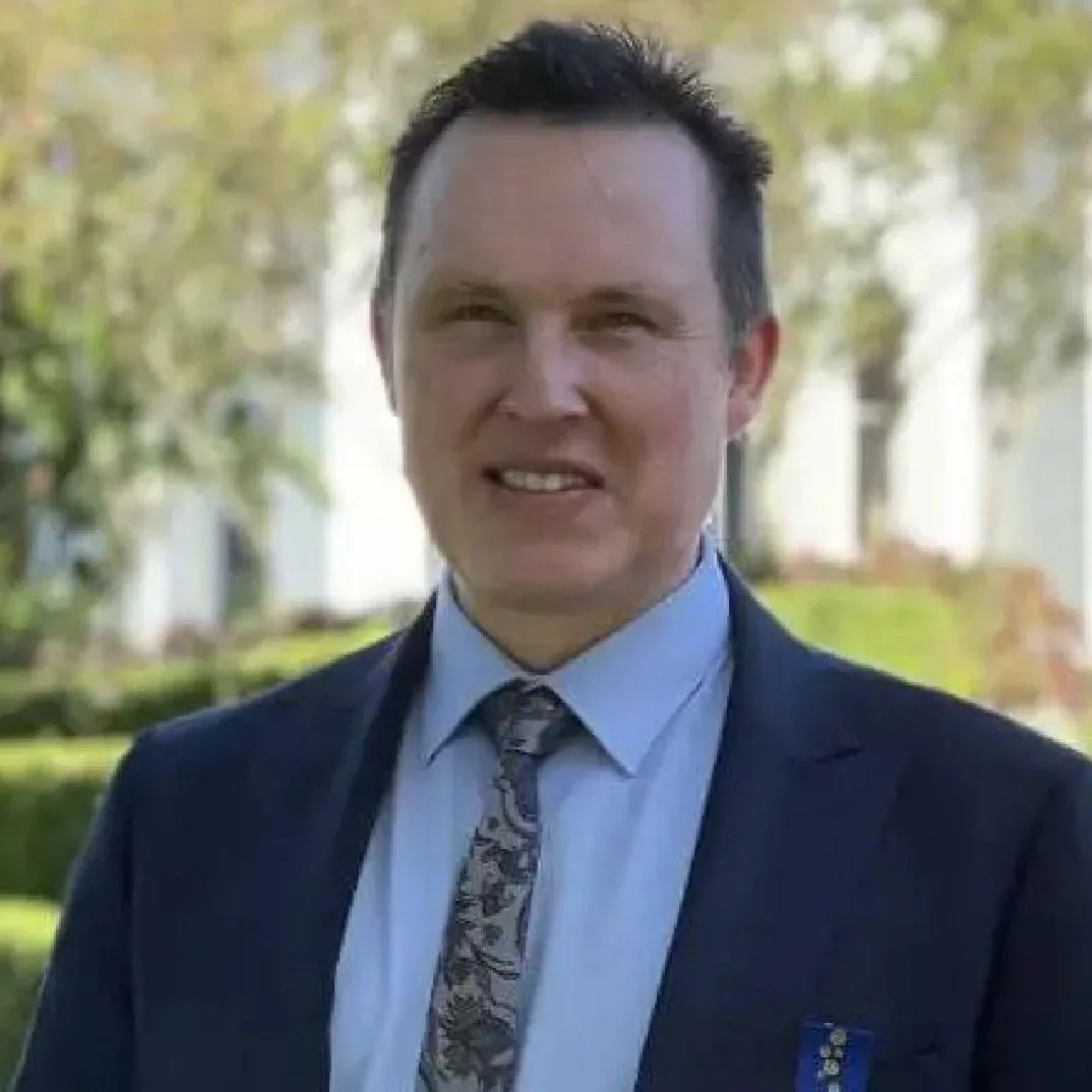 man in blue denim top standing under tree leaf