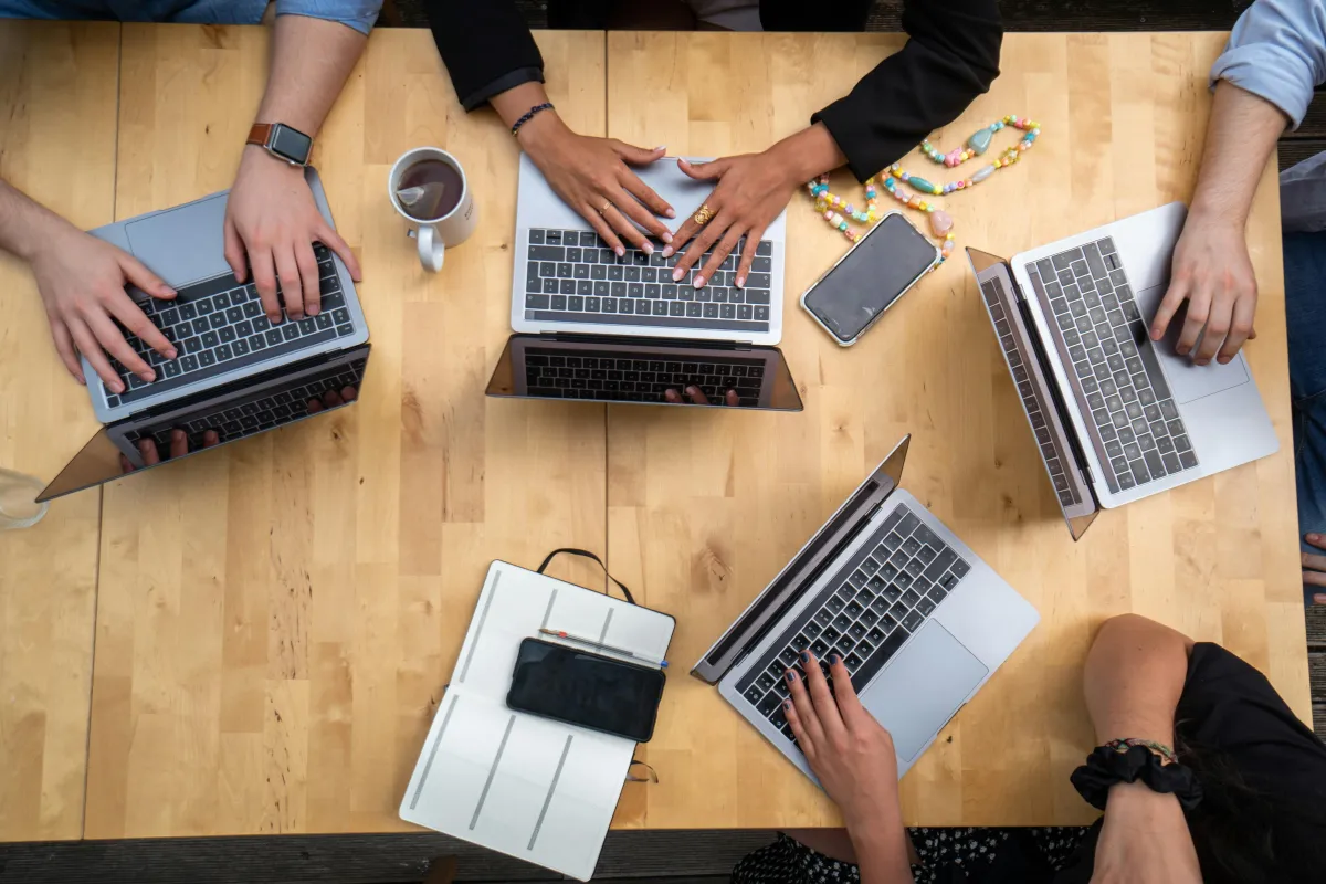 people sitting down near table with assorted laptop computers