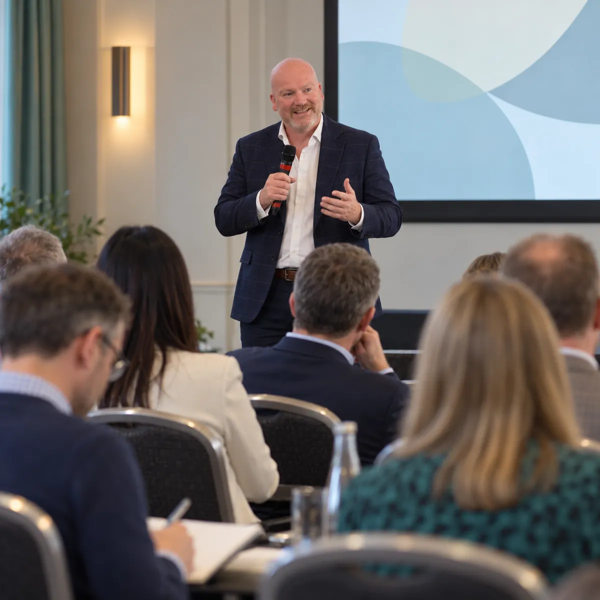 A business audience listening to Oliver Johnson deliver a practical keynote