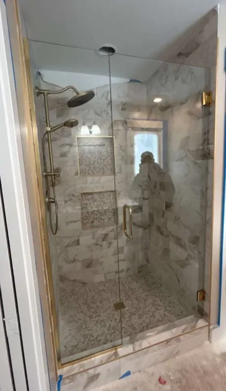 custom tile shower with glass door and gold trim