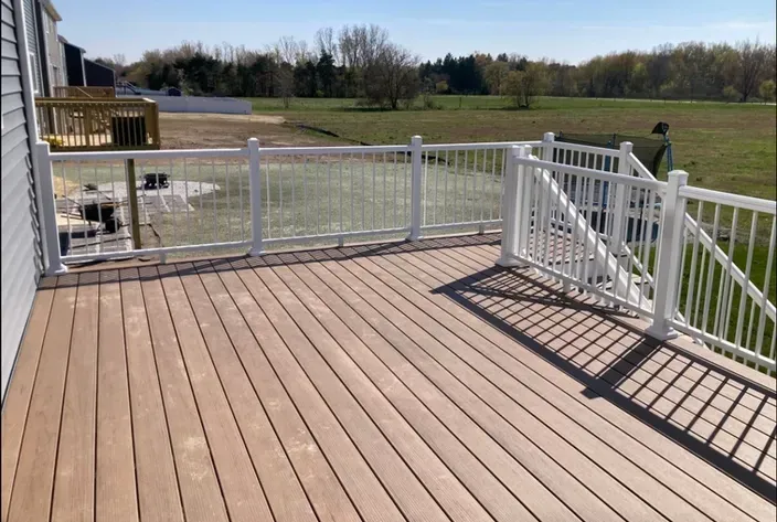 A composite deck with white railings, surrounded by open countryside and blue skies.