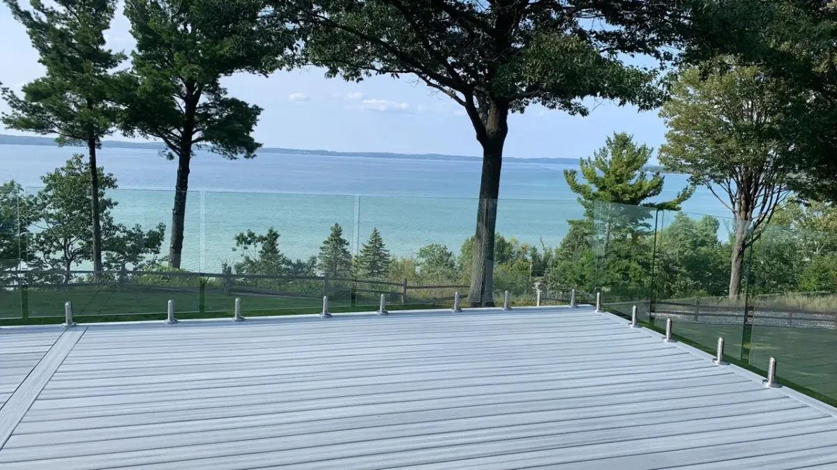 Lakeshore deck build with white planks and clear glass railing