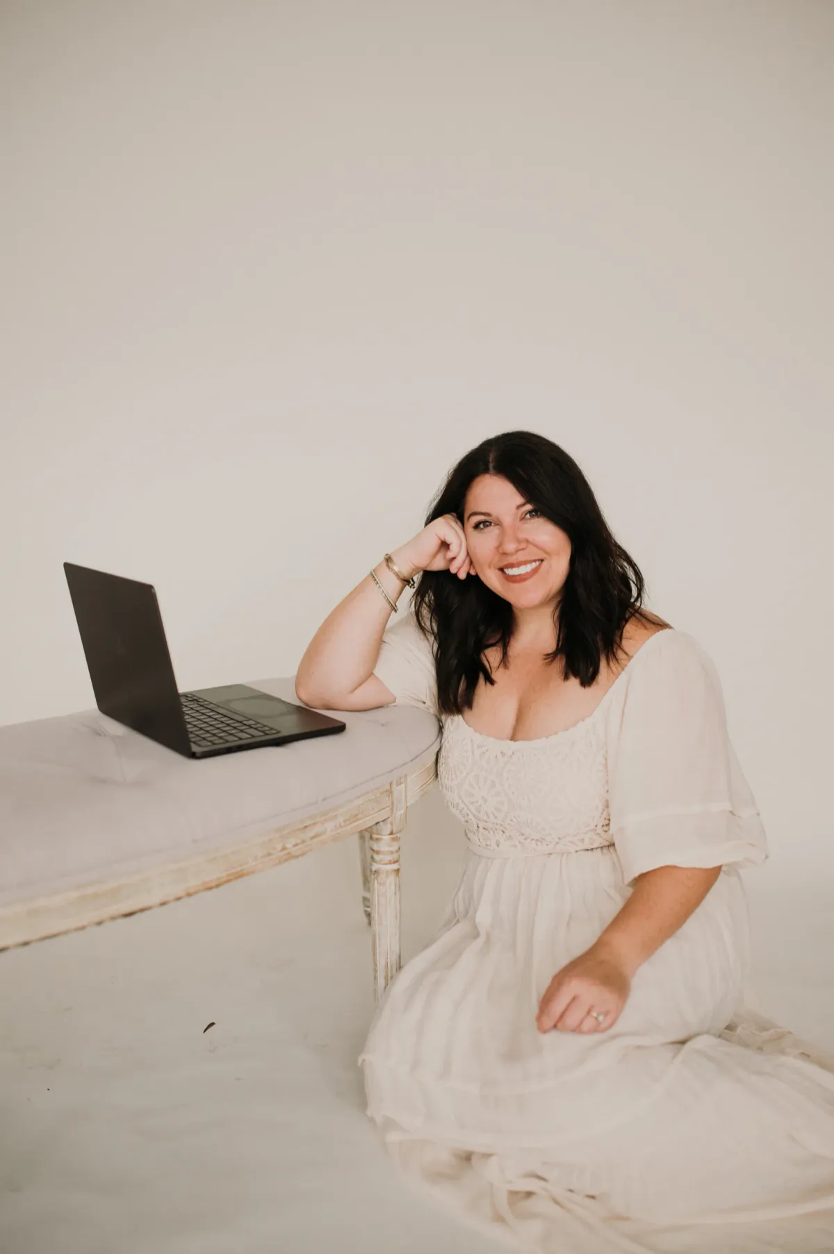 Woman sitting beside an open laptop in a bright minimalist studio. — how to drive more traffic to your website