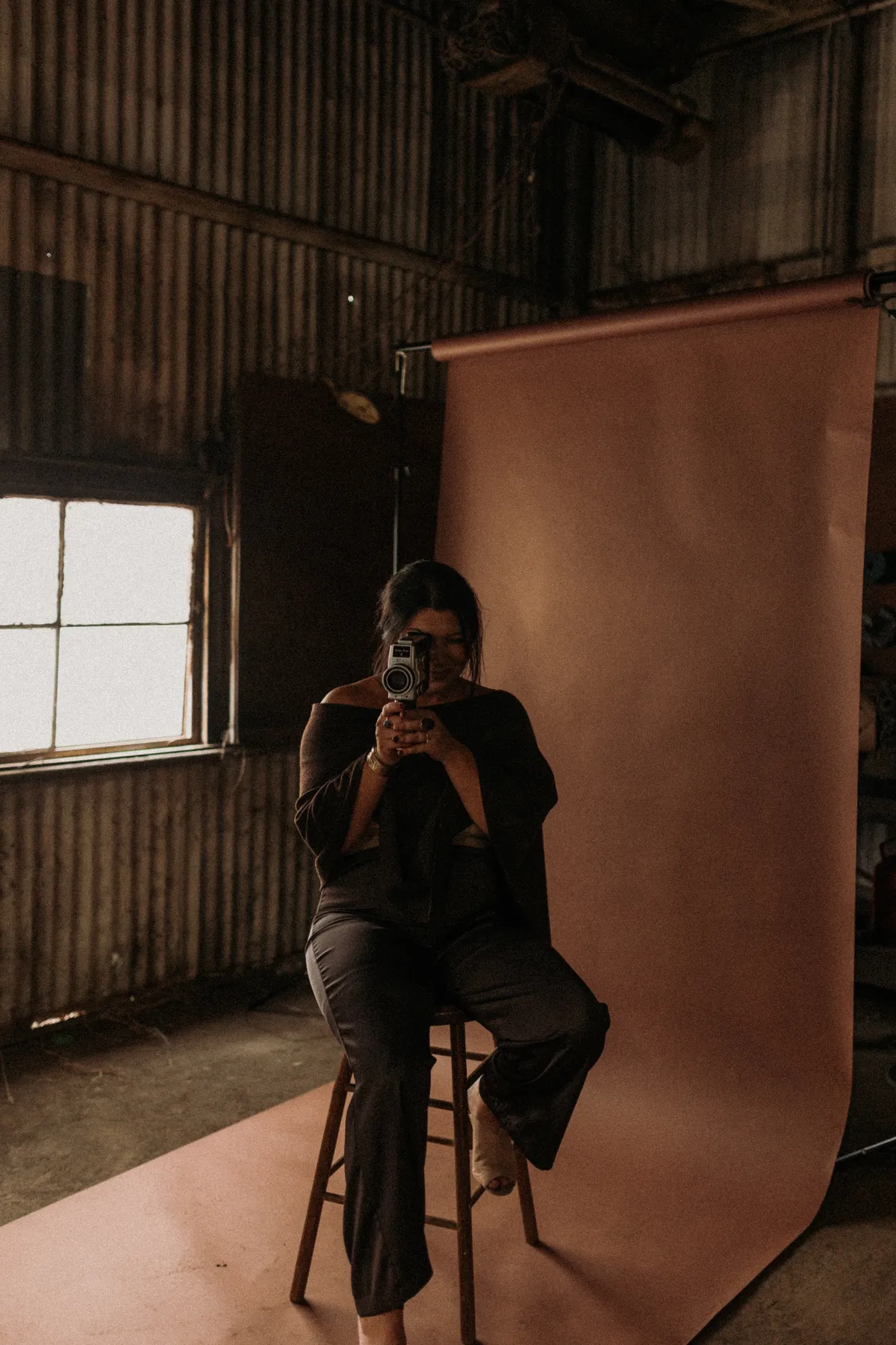 Courtney Prejean, founder of Coyote Brands, filming with a vintage camera in a Lafayette warehouse studio
