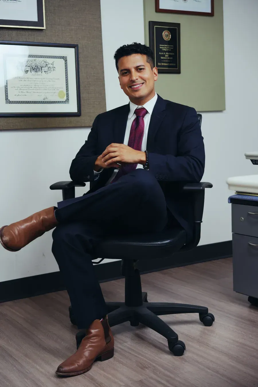 Eric Esteban Cardenas Lawyer in office chair with law degrees & bar licenses in background