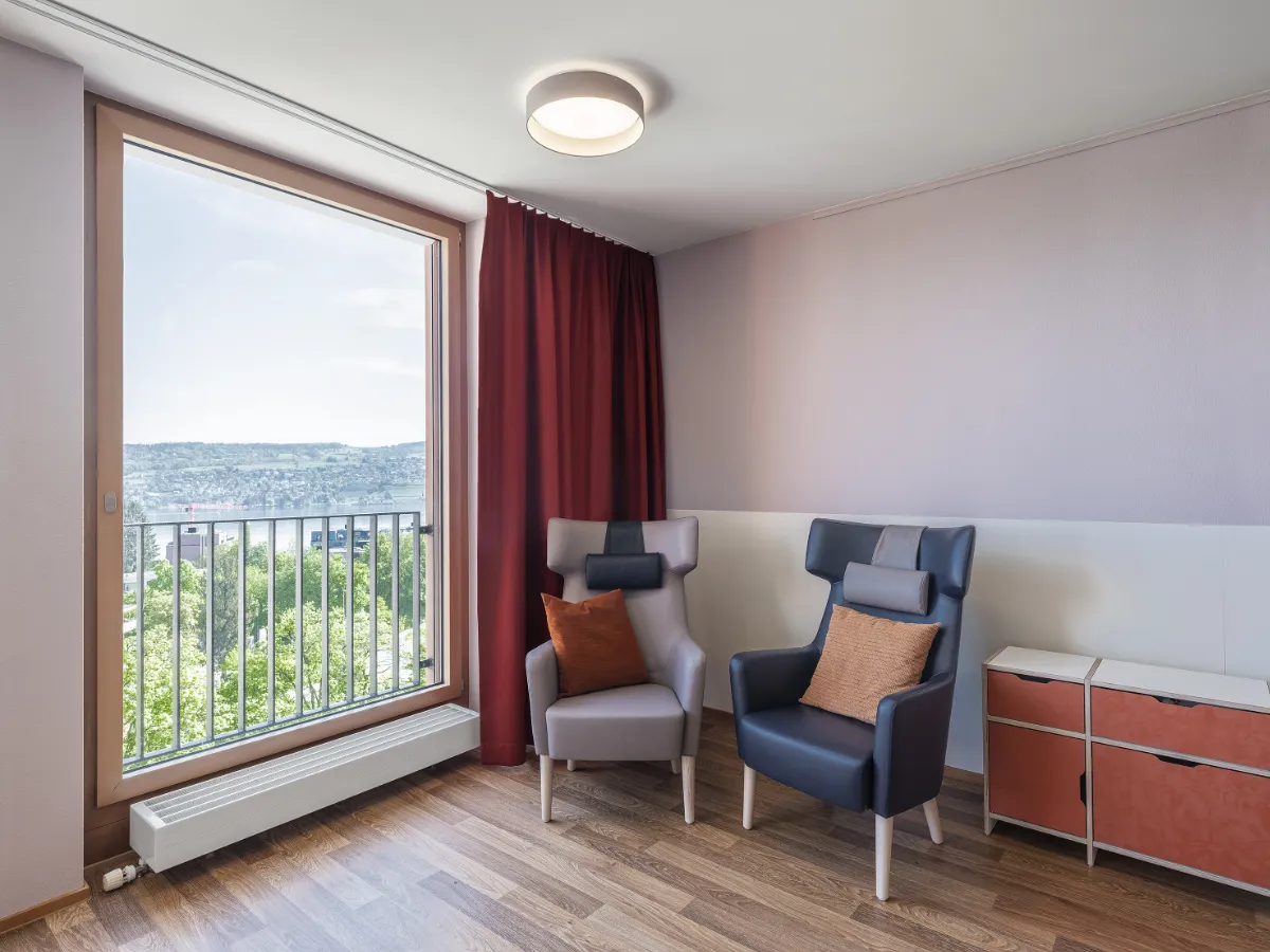 Wohnbereich für Menschen mit Demenz. Aufenthalt. zwei Ohrensessel mit Sideboard an Fensterfront.. Blick auf Zürichsee