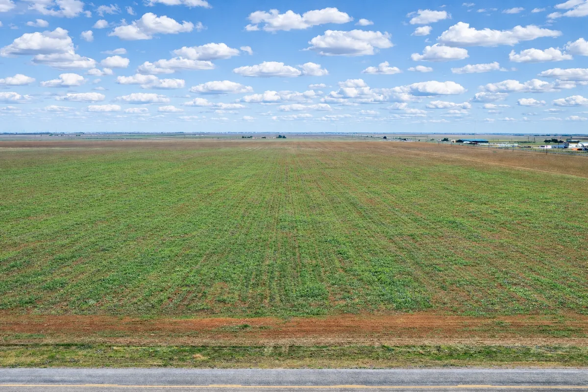 Aerial view of green farmland beside a paved road at Abernathy, 10-acre land for sale north of Lubbock, Texas