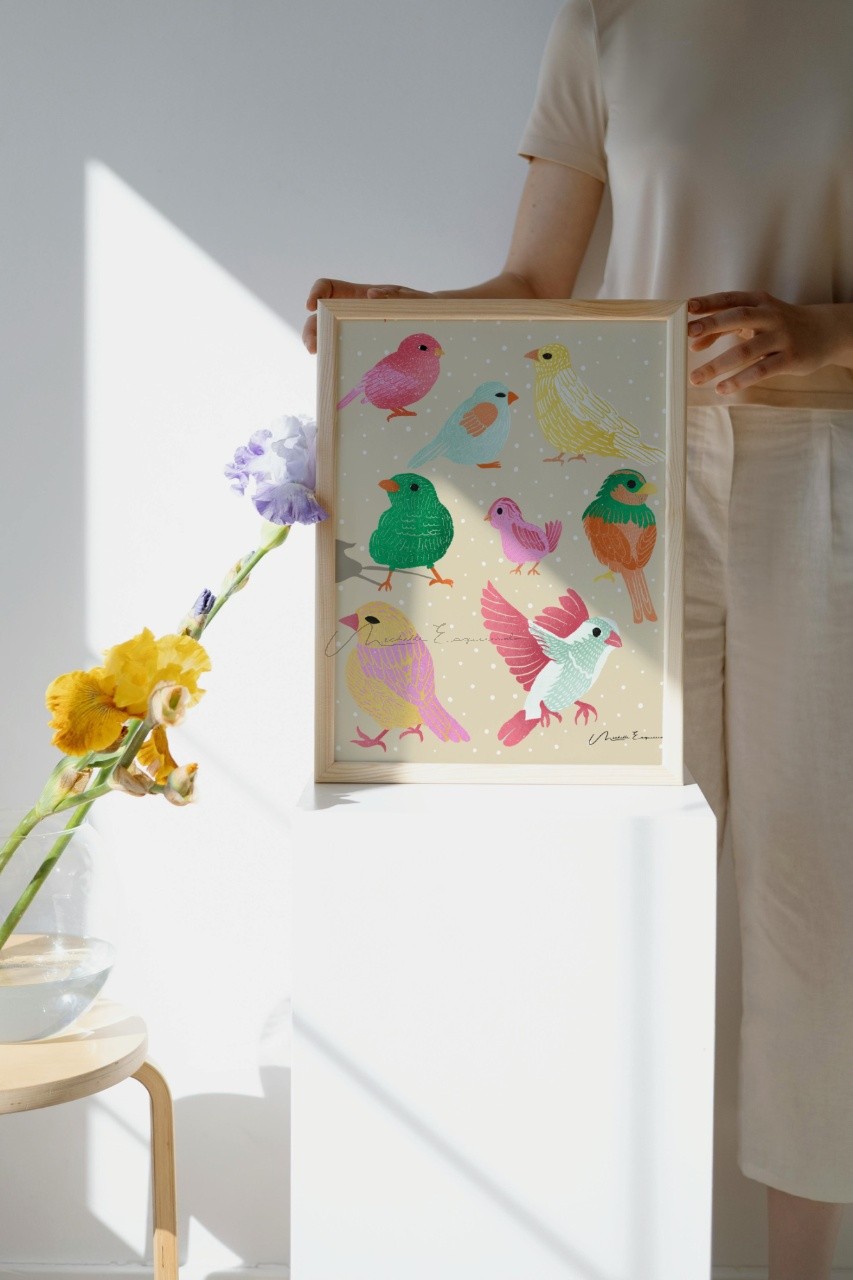 Woman holding a framed art print of the Flock Together bird illustration.