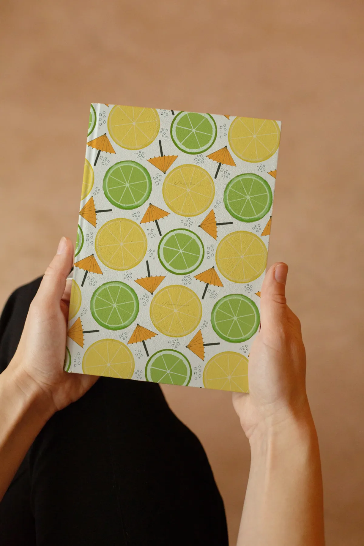Woman holding a journal featuring the Flock Together bird illustration from a licensable surface pattern collection.