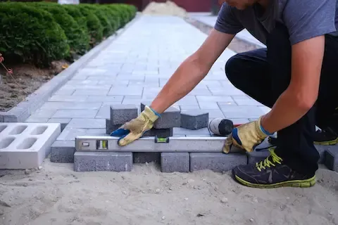 Contractor installing paver walkway with level tools – Gresham Concrete Services, Gresham OR.