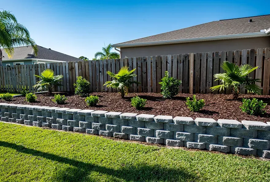 Finished stacked block retaining wall in a landscaped backyard in Kendale Lakes, Florida