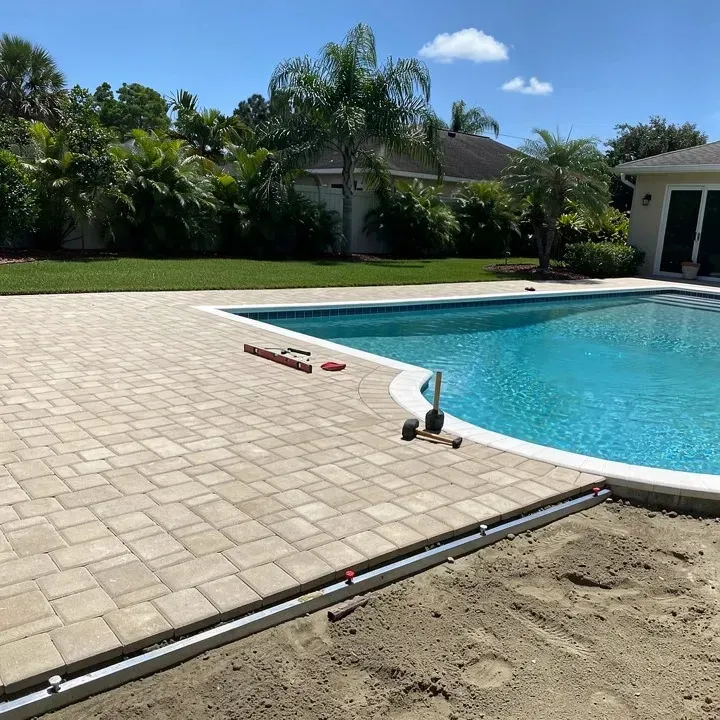Paver pool deck installation in progress around a backyard pool in Kendale Lakes, Florida