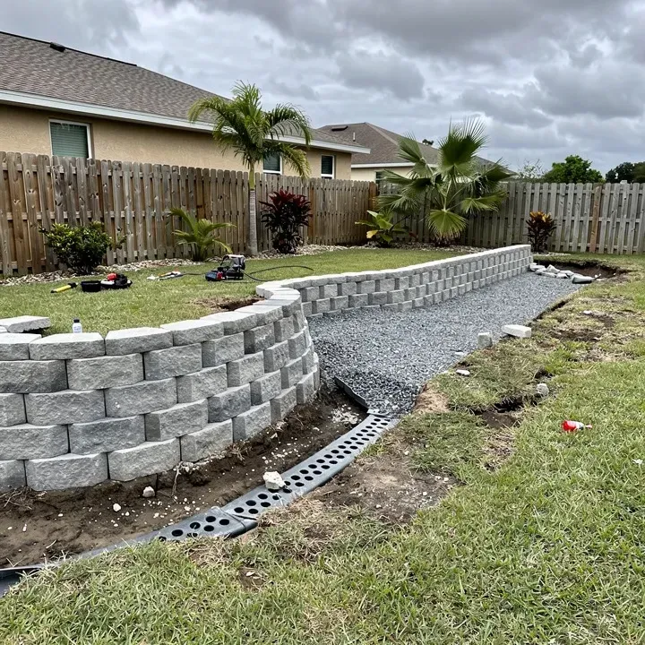 Retaining wall installation in progress under cloudy skies in Kendale Lakes, Florida