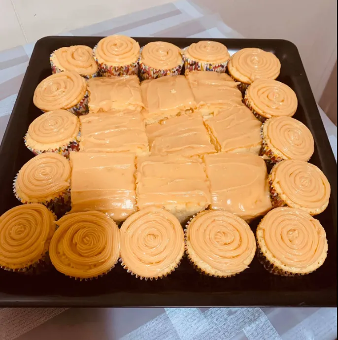 A jumbo caramel cupcake with a swirl of caramel frosting, set on a patterned plate with a playful polka dot napkin