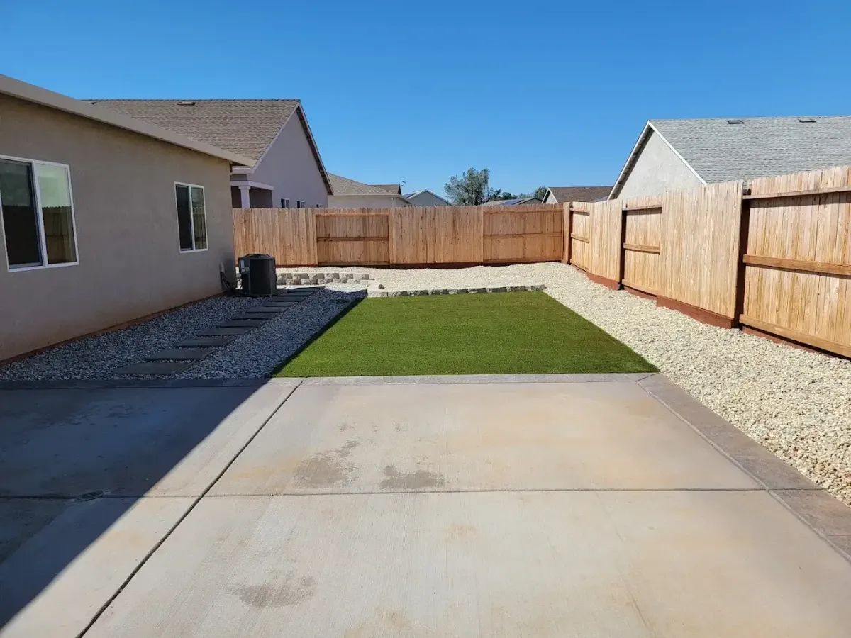 Backyard landscaping in Redding CA with turf lawn, gravel borders, stepping stone path, raised border, and wood fencing by Outdoor Artisans
