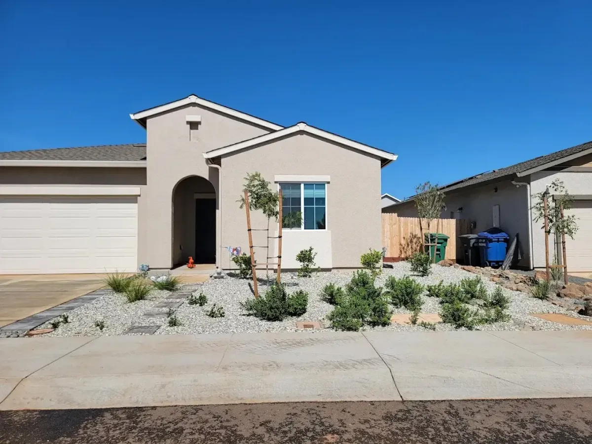 Front yard landscaping in Redding CA with white rock ground cover, stepping stone path, young trees, and drought-tolerant planting by Outdoor Artisans