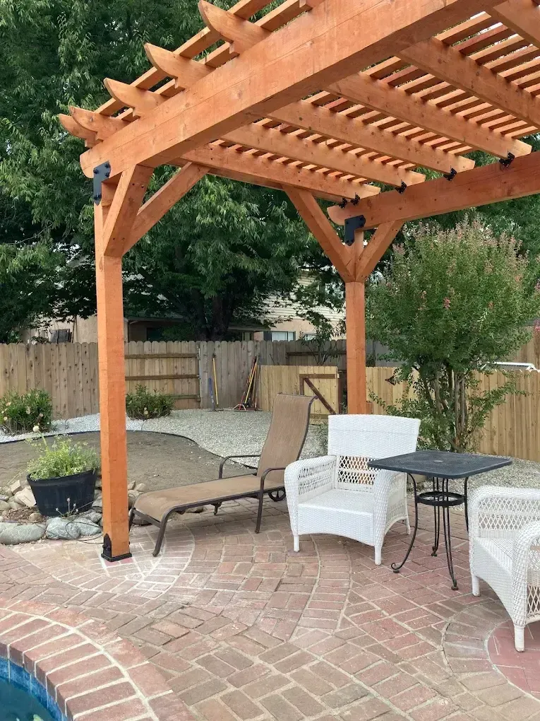 Wood pergola over a brick patio seating area in a backyard landscaping project in Redding CA by Outdoor Artisans