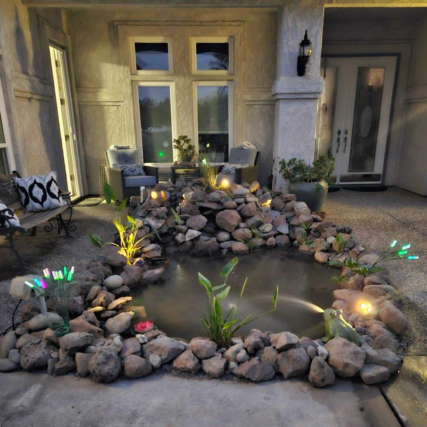 Front yard pond and rock water feature in a Redding CA landscaping project with aquatic planting and accent lighting by Outdoor Artisans