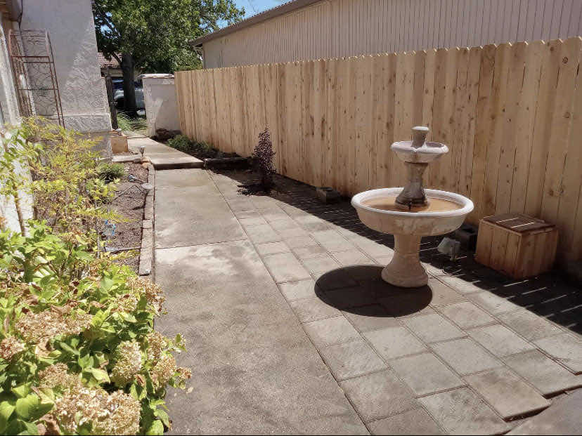 Fountain and concrete paver walkway in a Redding CA landscaping project with planting beds and wood fencing by Outdoor Artisans