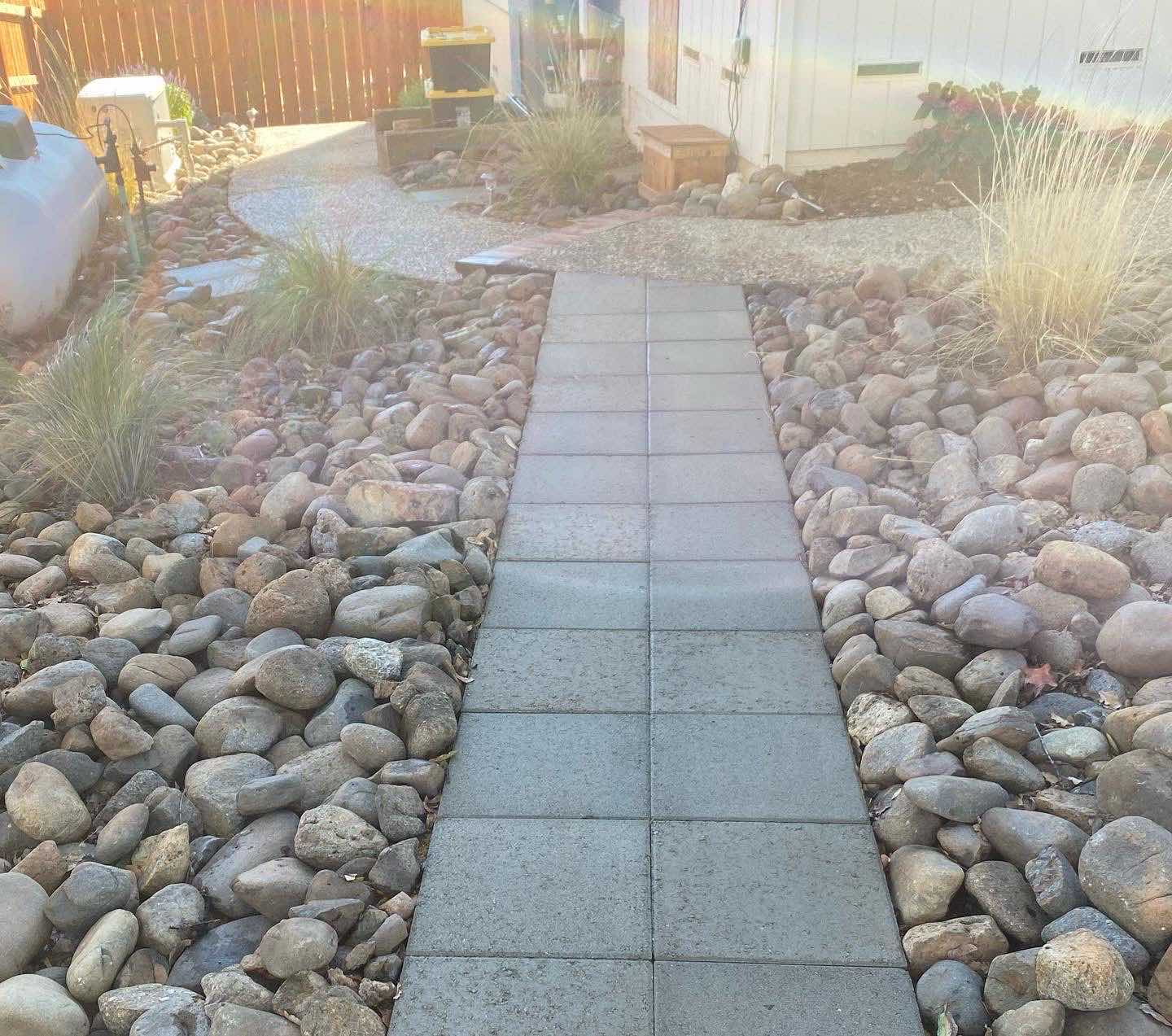 Concrete paver walkway in a Redding CA landscaping project with river rock borders and drought-tolerant planting by Outdoor Artisans