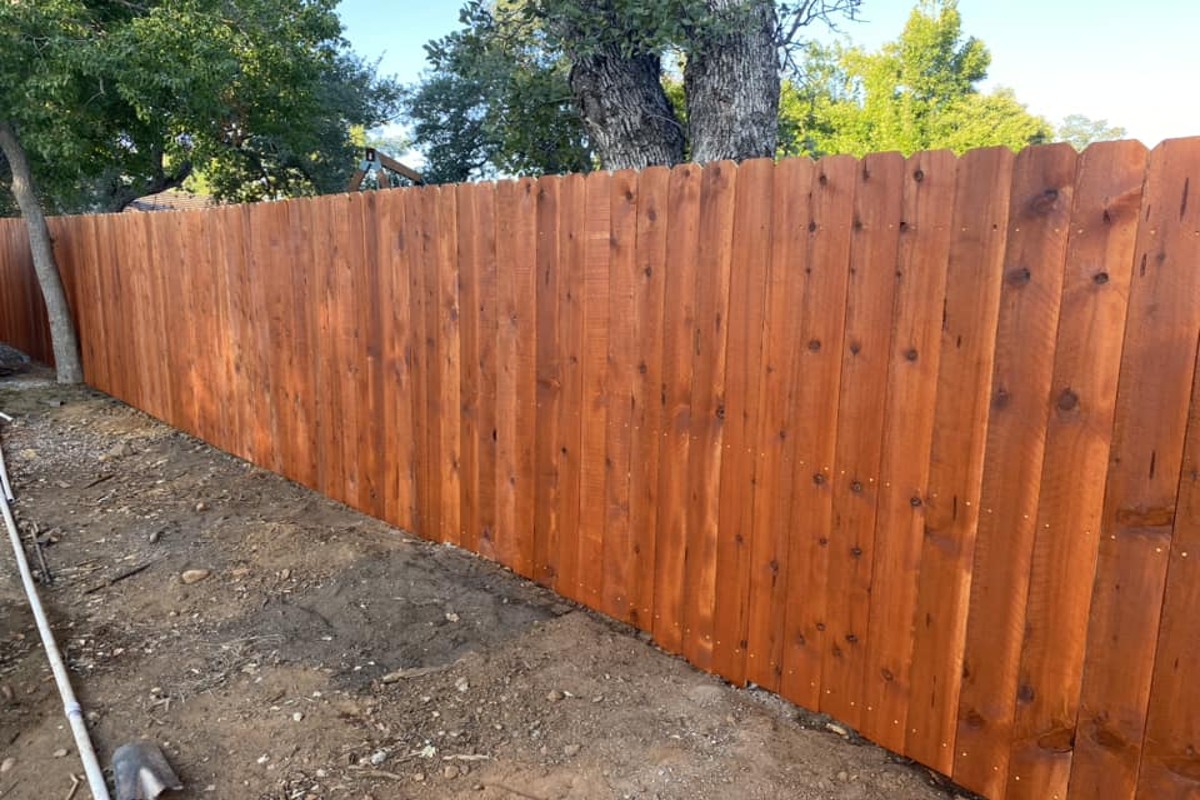 Stained wood privacy fence panels installed along backyard property line with clean finish