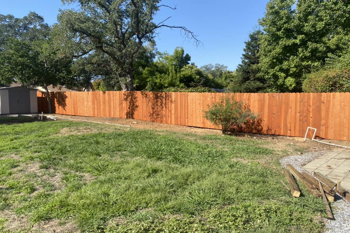 Wood privacy fence installation in backyard with clean straight fence line and natural wood finish